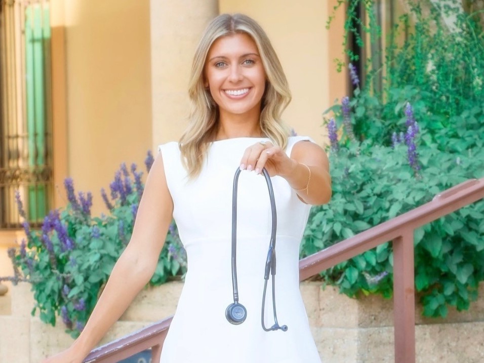 A nurse holds out a stethoscope.