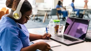 a young female Galen student studies with her laptop while wearing headphones