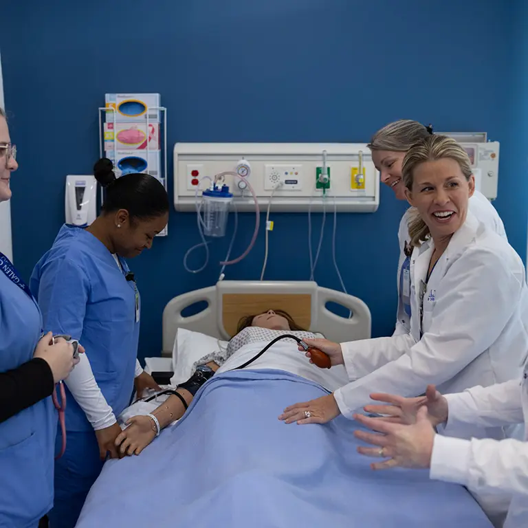 Galen nursing instructors and students gathered around a "patient" in the simulation lab